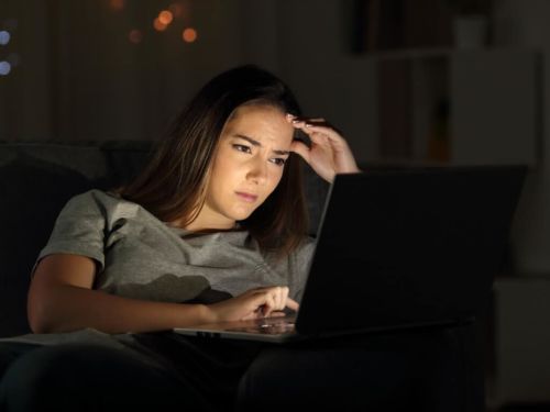 worried woman using laptop at night