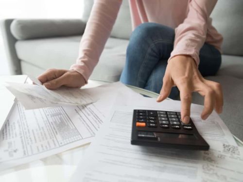 woman using calculator while surrounded by bills